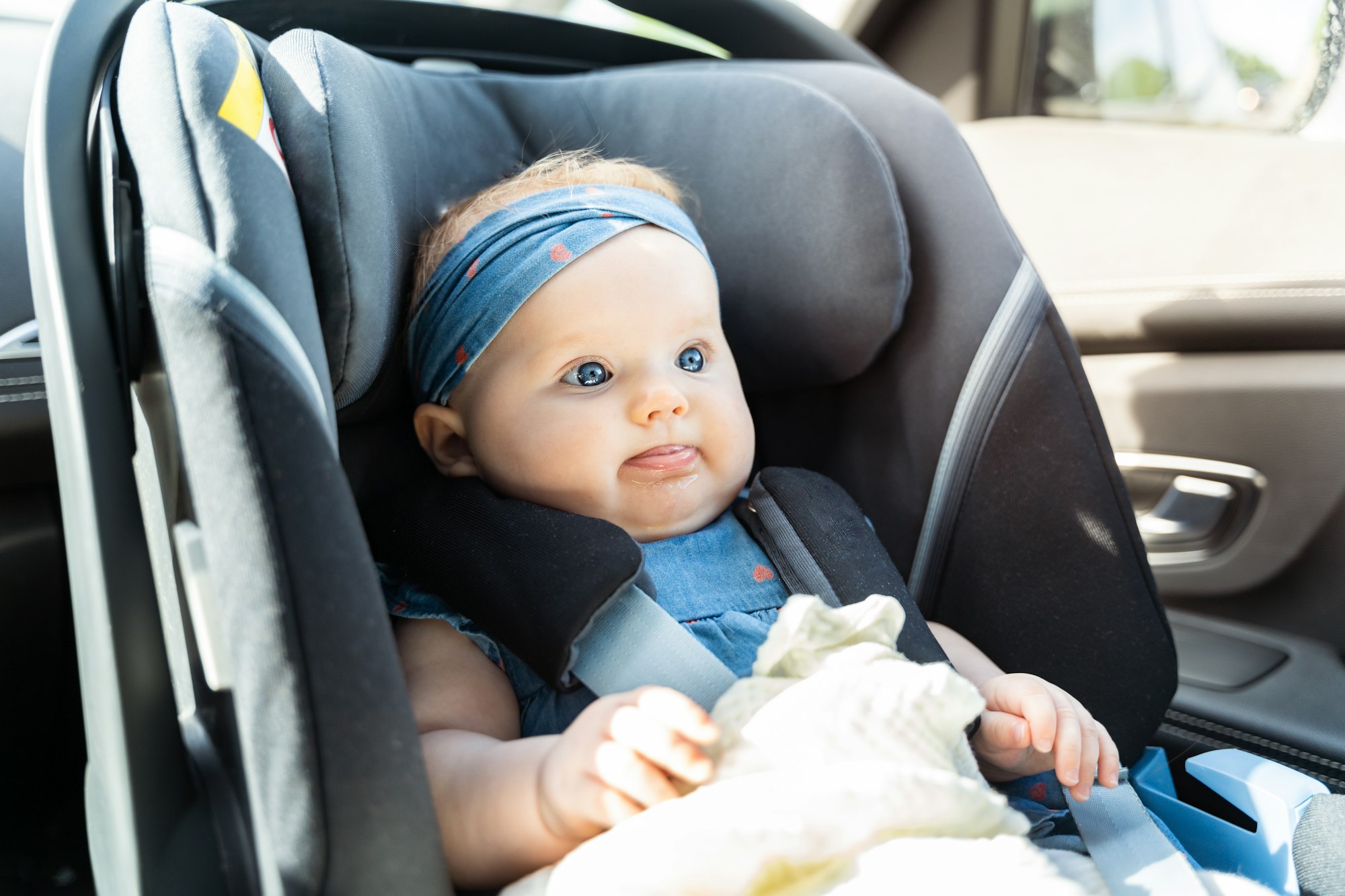 Baby girl sitting in an infant car seat, safety travelling by car with little child.